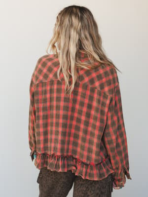 A back-view shot of a relaxed plaid flannel blouse with a ruffle hem and worn-in texture, paired with leopard print pants — the kind of outfit that feels intentionally effortless and a little unexpected.
