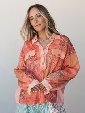 A patchwork button-up shacket in warm tangerine and plum tones layered over a green striped bottom — the kind of piece that looks like it was made from someone's favorite vintage scarves and immediately becomes yours.
