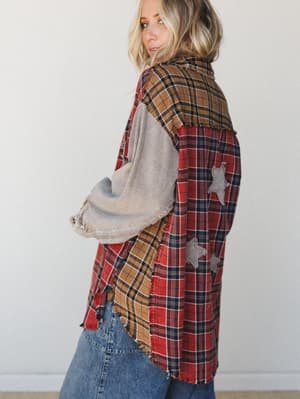 A patchwork plaid flannel top shot from the back at a three-quarter angle, mixing red, tan, and grey plaids with raw frayed edges and star appliqués — the kind of top that looks like it has a great story already.