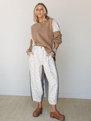 A relaxed, lived-in outfit pairing a mocha colorblock sweatshirt with lace sleeve inserts and cropped floral wide-leg pants — the kind of put-together-but-cozy look that feels effortless on a cool morning.