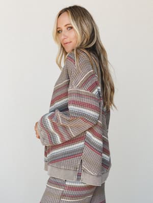 A relaxed, oversized waffle-knit pullover in a warm multi-stripe pattern — the kind of top that looks like it came from a really good thrift store, in the best possible way.