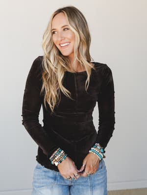 A velvet long-sleeve top in deep espresso brown paired with light wash jeans and stacked boho bracelets — the kind of effortless outfit that looks like you tried just enough.