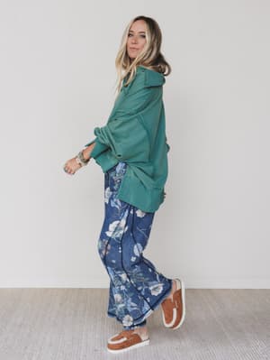 Green / Woman wearing a green jacket and blue floral pants on a plain background
