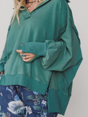 Green / Person wearing a teal oversized sweatshirt with a plain background