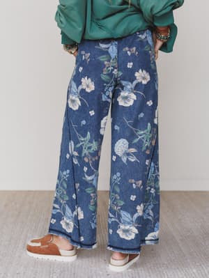 Green / Person wearing blue floral pants with a plain background