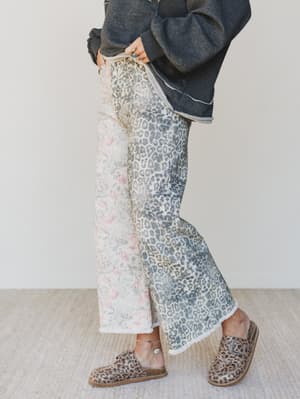 Person wearing patterned pants and leopard print shoes on a plain background