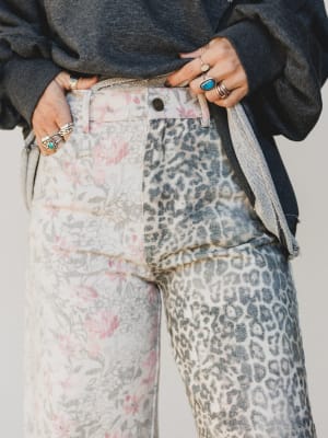 Person wearing floral and leopard print pants with a neutral background