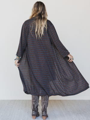 Person wearing a long, dark plaid coat against a white background