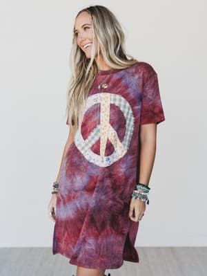 Woman wearing a tie-dye dress with a peace symbol design on a plain background