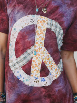 T-shirt with a peace symbol design made of fabric patches on a tie-dye background.