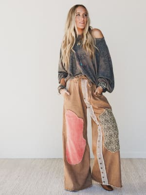 Woman wearing a stylish outfit with a brown wide-leg pants and a dark top against a plain background