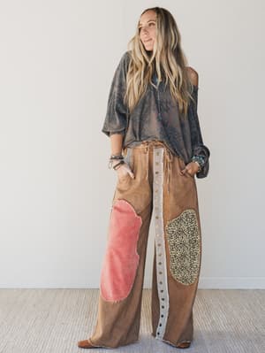 Woman wearing a stylish outfit with a patterned top and brown pants with patches.
