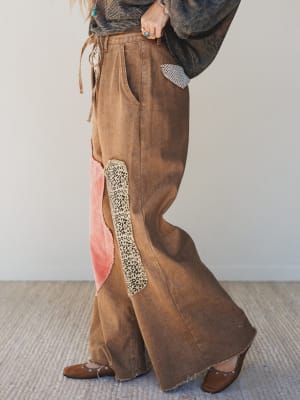 Brown wide-leg pants with a decorative patch on a neutral background