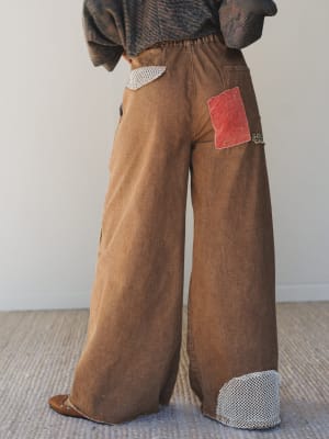 Brown corduroy pants with patches on a neutral background