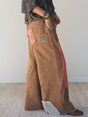 Brown corduroy pants with pink and leopard print accents worn by a person on a neutral background