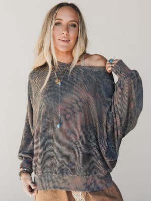 Woman wearing a sheer off-shoulder top against a plain background