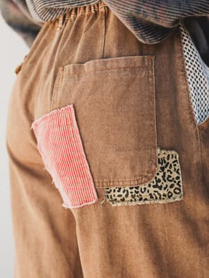 Brown pants with pink and leopard print patches on a white background