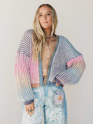 Woman wearing a colorful striped cardigan with a neutral background