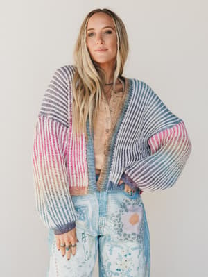 Woman wearing a colorful striped cardigan with a neutral background