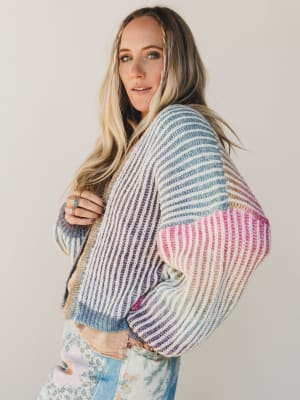 Woman wearing a colorful striped sweater against a plain background