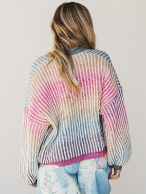Person wearing a colorful knitted sweater with a neutral background