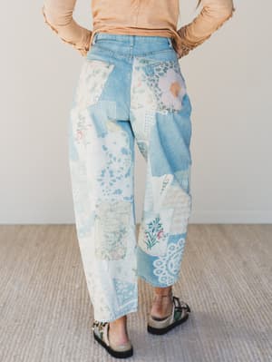 Person wearing a pair of floral and patchwork patterned pants on a neutral background