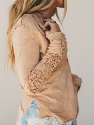 Beige sweater with lace sleeves worn by a person against a neutral background