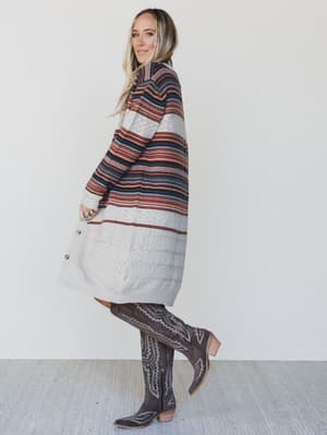 Woman wearing a striped sweater and patterned boots on a plain background