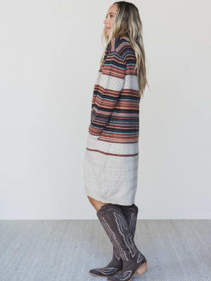 Woman wearing a striped dress and cowboy boots against a white background