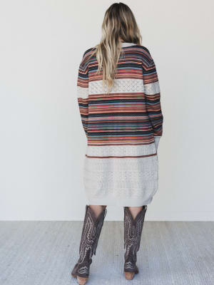 Woman wearing a striped sweater and patterned pants with a white background
