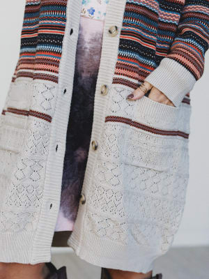 Close-up of a person wearing a patterned cardigan with a white lace trim.