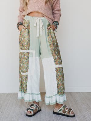 Person wearing colorful patchwork pants with a plain background