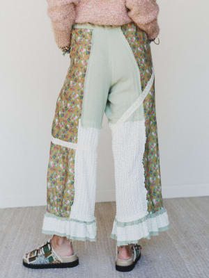 Person wearing a floral skirt with a white top and light-colored pants against a plain background