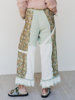 Person wearing a floral skirt with a white top and light-colored pants against a plain background