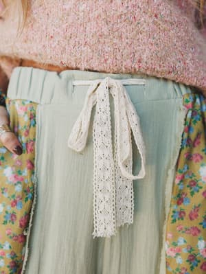 Person wearing a light green skirt with a lace ribbon and floral top.