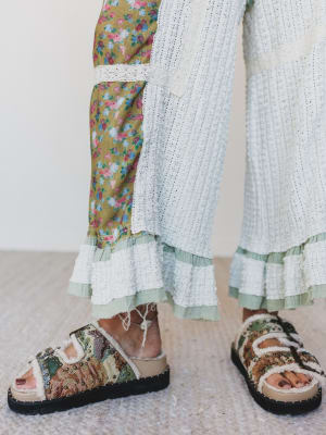Person wearing floral sandals with a colorful outfit on a light background