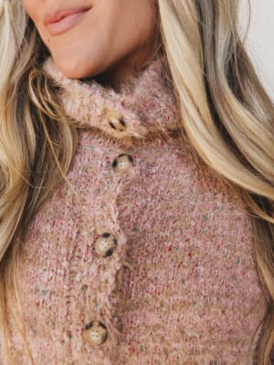Close-up of a person wearing a textured pink coat with buttons.