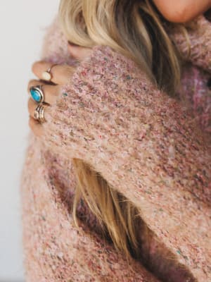 Close-up of a person wearing a textured pink sweater with a blurred background