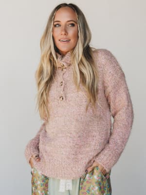 Woman wearing a pink knitted sweater with a plain background