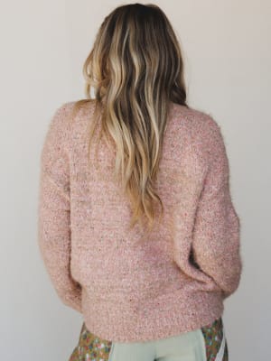 Person wearing a pink sweater with a neutral background