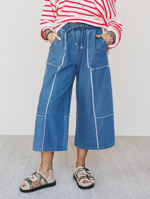 Person wearing a red and white striped shirt with blue wide-leg jeans on a light background