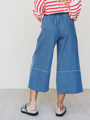 Person wearing a red and white striped shirt with blue wide-leg jeans on a plain background