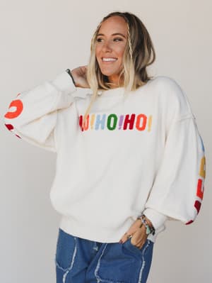 Person wearing a white sweatshirt with colorful text on a plain background