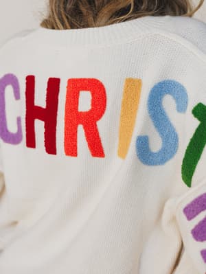 Back view of a person wearing a colorful 'CHRIS' sweater with a neutral background.