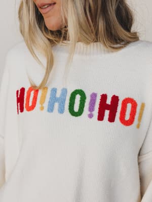 Close-up of a sweater with colorful 'HO! HO! HO!' text.