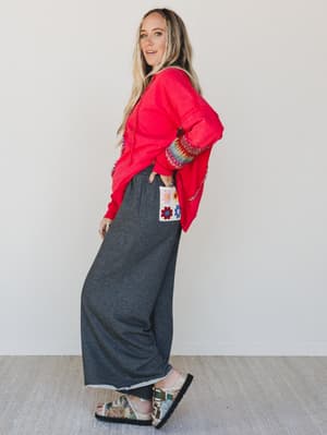 Woman wearing a red jacket and gray pants with a white background