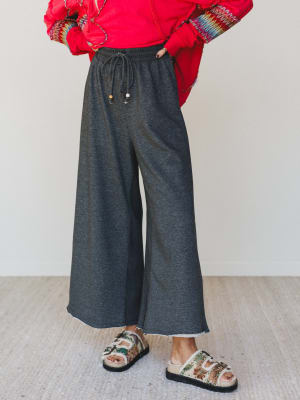 Person wearing a red sweater and gray wide-leg pants on a plain background