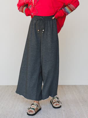 Person wearing a red jacket and gray wide-leg pants on a plain background