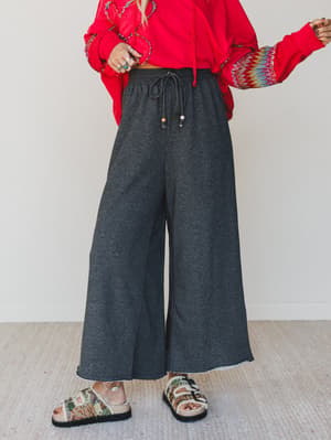 Person wearing a red sweater and gray wide-leg pants on a plain background