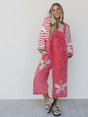 Woman wearing a red denim dress with decorative bows and a striped top against a white background